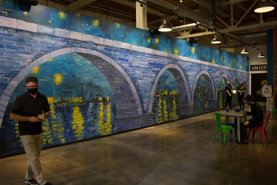 Un murale con un ponte ad arco in pietra dipinto in uno stile misterioso che ricorda Van Gogh