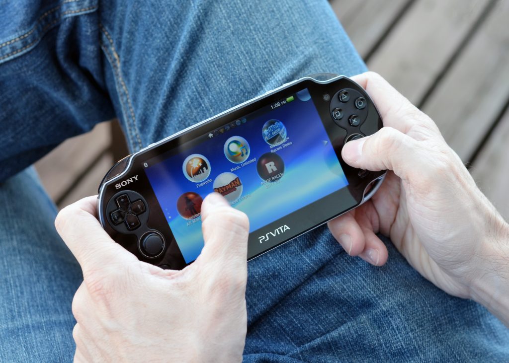 'Vancouver, Canada -- April 7, 2012: Close up of a man playing on a PS Vita video game system. The PS Vita is a newest portable gaming console from Sony.'