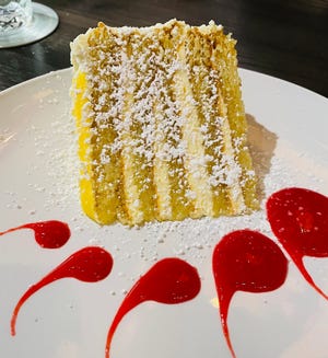 La torta alla crema al limone italiana di Bella è una torta bianca condita con uno strato di crema al limone e condita con una pioggerellina di lamponi.