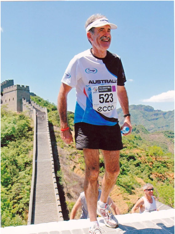 Runner in piedi in cima alla maratona della Grande Muraglia sotto un cielo limpido.