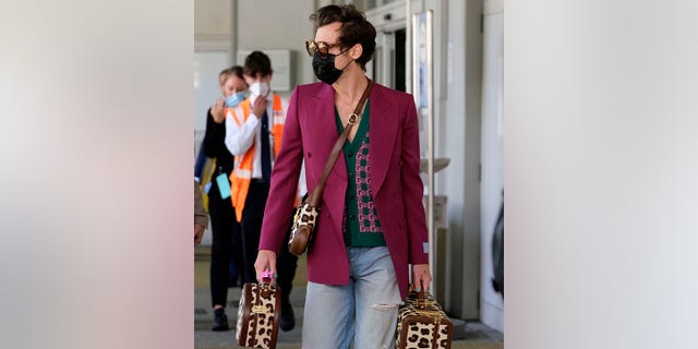 Harry Styles passeggia per l'aeroporto in Italia con una valigia leopardata.